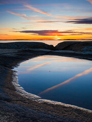 Sunset over coastal reflections near Gothenburg in Sweden with serene waters and rocky shores