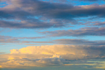 Obraz premium Evening clouds of various hues fill the sky, from grey to golden, against a backdrop of blue. This creates a dynamic and captivating sky landscape, full of transitional colors.