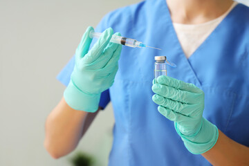 Female doctor with ampoule and syringe in clinic, closeup
