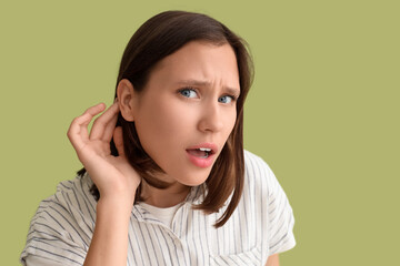 Young woman with hearing problem on green background, closeup