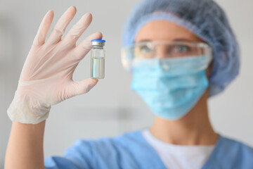 Fototapeta premium Female doctor in medical mask with ampoule at hospital, closeup