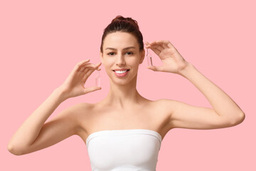 Beautiful young woman with ampoules on pink background
