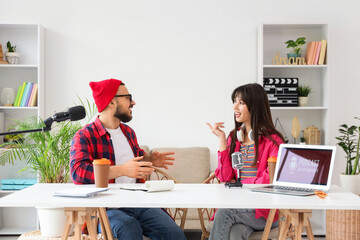 Couple of podcasters talking at table in recording studio