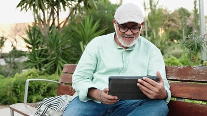 Middle eastern man on a video call talking to family using tablet in public park - Powered by Adobe