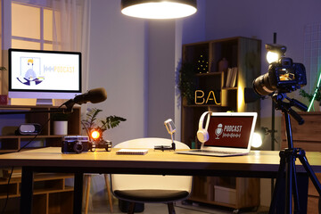 Podcaster's workplace with laptop and microphones in dark studio
