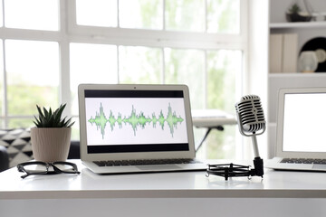 Laptop with record and microphone on podcaster's table in studio, closeup