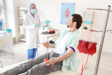 Blood pack for transfusion against donor with doctor in clinic, closeup