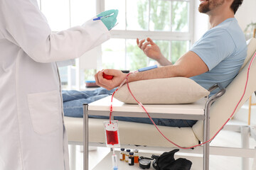 Young man donating blood with doctor in clinic