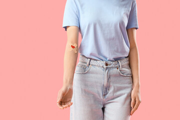 Female blood donor with medical patches on pink background
