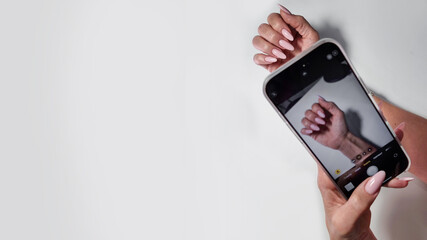 A close-up shot of a hand with a beautiful manicured nails holding an iPhone, capturing a photo or selfie.  Perfect for themes related to beauty, manicure, social media, technology, or lifestyle. Nail