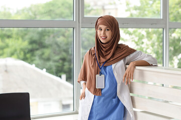 Female Muslim medical intern near reception in clinic