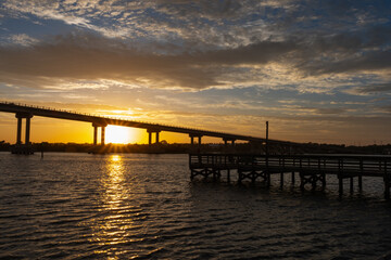 A pier running out into the bay at sunset along the intercostal waterway at the beach taken while on vacation.