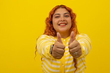 Red haired freckled woman wearing a yellow shirt with white stripes, has a happy expression with...