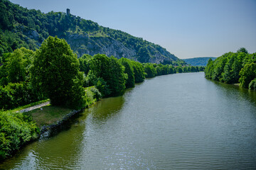 Serene river flowing through lush greenery with hills in the background on a sunny day