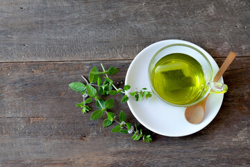 Cup of mint tea and leaves of mint on wood table.