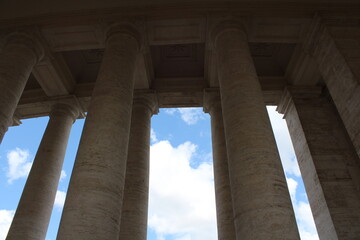Columned hallway in Saint Peter-s Square. Beautiful ancient architecture with huge marble pillars and blue sky background. Ancient architectural background wallpaper. Vatican pillars
