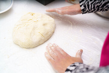 Hands knead dough on a countertop during a home baking session in a cozy kitchen setting