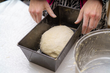 Baking dough in a kitchen with hands preparing for the oven at home during the afternoon