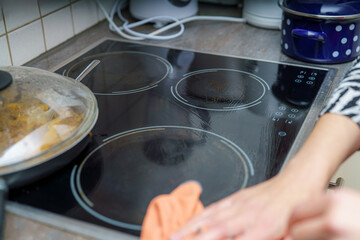 Cleaning the stovetop after cooking a meal in a home kitchen during the afternoon