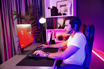 Wearing headphones smart gaming streamer enjoy playing car racing online game on pc screen to be champion with final competition in lifestyles on weekend at neon digital cyber lighting room. Surmise.