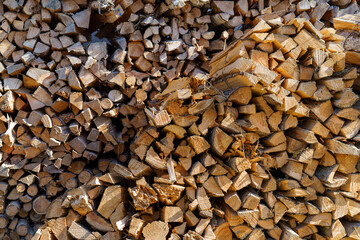 Firewood stacked in natural arrangement with sunlight highlighting the textures and colors in a rural setting during afternoon