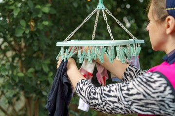 Woman hanging clothes on a clothesline in a garden during daylight hours