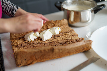 Preparing a delicious cake with whipped cream on a kitchen countertop during daytime