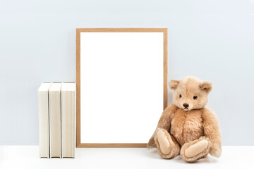 minimalist nursery art mockup with blank wooden picture frame and a vintage teddy bear / children's toy and books  on a white shelf or desk against a light blue wall, simply insert your artwork