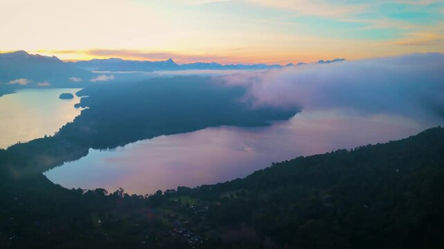 Stunning aerial view of Lake Nahuel Huapi surrounded by morning mist and mountain peaks in Villa La Angostura, Patagonia, Argentina. The scene includes iconic landmarks 