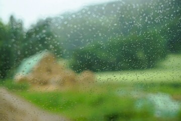 Abstraktes grünes Landschaftspanorama mit Heuballen auf grüner Wiese, Bäumen, Wald und Himmel auf dem Land bei Regen am Abend im Sommer