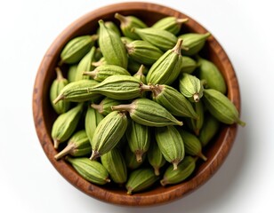 Wooden bowl filled with vibrant green cardamom pods. Culinary herb ingredient with unique shape and texture. Perfect for cooking flavoring seasoning food preparation. Top view on white.