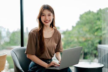 Beautiful Asian woman holding laptop and smiling at cafe. Freelancer working.