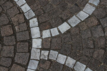 Contrast of grey and white cobblestones on textured pavement surface.
