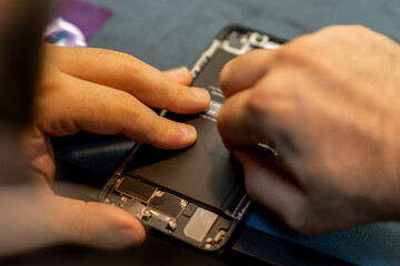 Phone Repair Technician Replacing Battery in Smartphone Inside Workshop During Daylight Hours