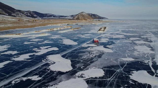 Drone panorama of vehicle crossing frozen lake Baikal with hovercraft in winter landscape, Russia.