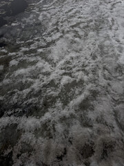 Partially melted ice on water surface in abstract style, textured gray and white tones, seasonal thaw and climate transition representation