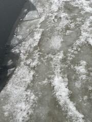 Broken river ice with textured surface in natural style, gray and white tones, symbolizing environmental fragility and seasonal melting