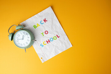 Time for back to school concept with clock and notebook paper on school bus yellow background