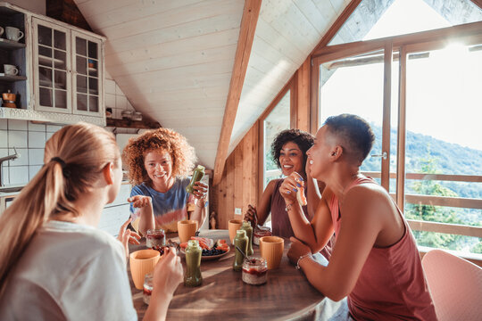 Young and diverse gorup of female friends having breakfast together in a cabin in the forest