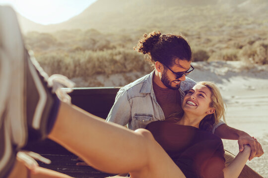 Happy couple relaxing together in the back of a pickup truck on a sunny day - Powered by Adobe