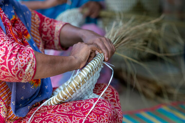 Woman Weaving a Basket with Natural materials. Hands weaving a straw basket. Ancient Indian's hand...