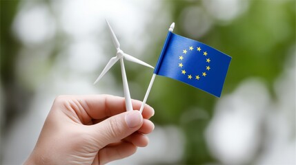 Hand holding a wind turbine model and European flag representing clean energy