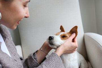 Young woman playing with her dog at home. Copy space, background.