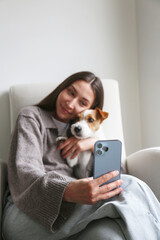 Young woman taking selfies with her dog. Copy space, background.