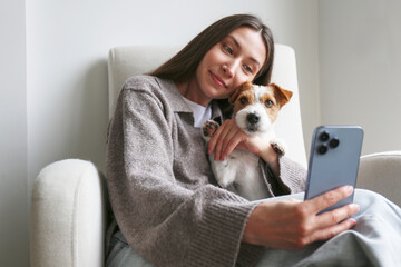 Young woman taking selfies with her dog. Copy space, background.