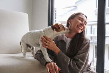 Young woman playing with her dog at home. Copy space, background.