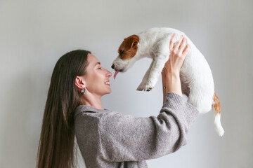 Young woman playing with her dog at home. Copy space, background.