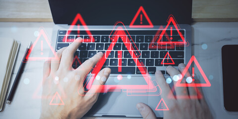 Hands typing on laptop keyboard with multiple red exclamation mark warning icons overlaid,...