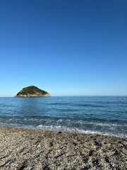 Peaceful Pebble Beach with Clear Blue Sea and Small Island on the Horizon Under Bright Sky, Serene Coastal Landscape Perfect for Summer Getaway, Nature Escape and Relaxed Travelgram Moments