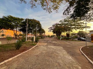 A park pathway with trees and buildings under a bright sky during the daytime in a peaceful scene